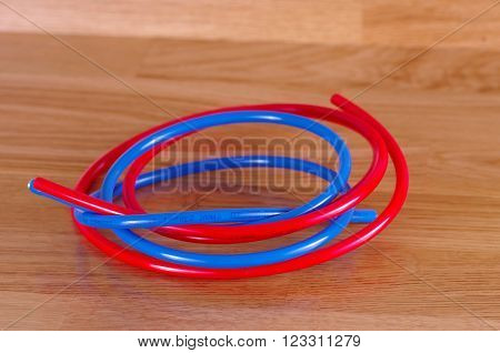 Red and blue Plastic Pipe 's on wooden table.