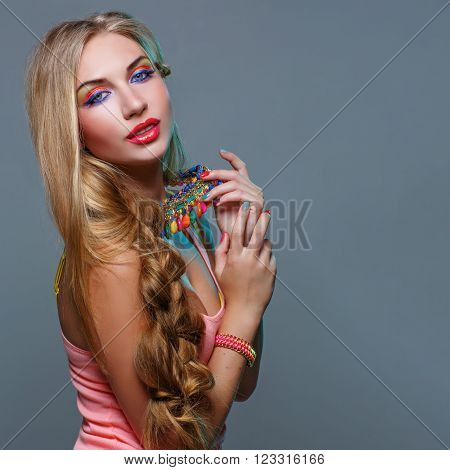 Closeup portrait of beautiful young woman with bright colorful makeup and matching neclace. Emotions. Over grey background.