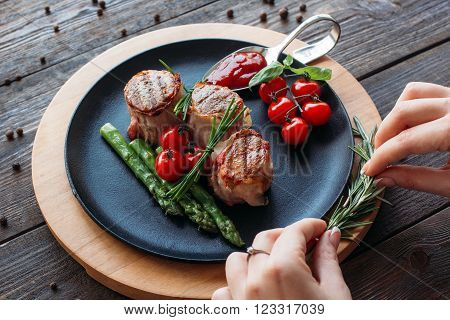 Chief decorating a pork dish. Waiter serving food for presentation to the client. Chief decorating food for retail.