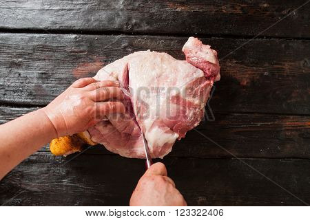 Slicing pork meat on piece in farm market.  Butcher slicing pork meat in local market. Top view on old wooden background