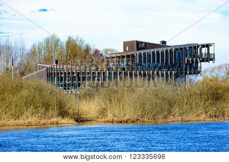 Kristianstad Sweden - March 20 2016: The Vattenriket Naturum building seen from across the river. The river flows in the foreground. Early spring on a sunny day.