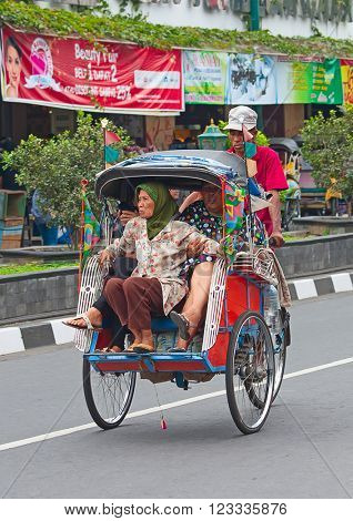 YOGYAKARTA - AUGUST 03: Traditional rikshaw transport on streets of Yogyakarta, Java, Indonesia on August 03, 2010. Bicycle rikshaw remains popular means of transport in many Indonesian cities.