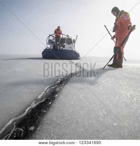 Saint-Petersburg Russia - March 27, 2016: A member of the rescue team checks the thickness of the ice in the Gulf of Finland where the ice fishermen out.