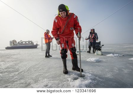 Saint-Petersburg Russia - March 27 2016: A member of the rescue team checks the thickness of the ice in the Gulf of Finland where the ice fishermen out.
