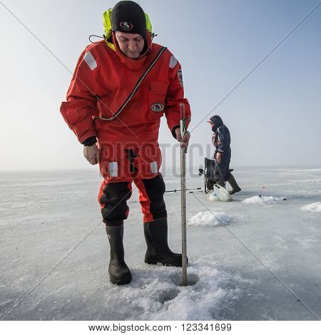 Saint-Petersburg Russia - March 27 2016: A member of the rescue team checks the thickness of the ice in the Gulf of Finland where the ice fishermen out.