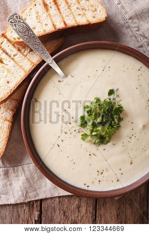 White vegetable cream soup close up in a bowl. vertical top view