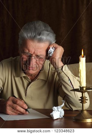 Portrait of a mature man writes something near candle