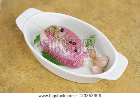 raw ham with rosemary and laurel in dish