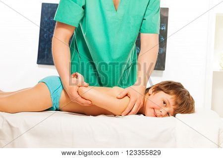 Little boy lying at the massage couch at the light rehabilitation cabinet