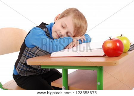 Boy fell asleep at a school desk isolated on white