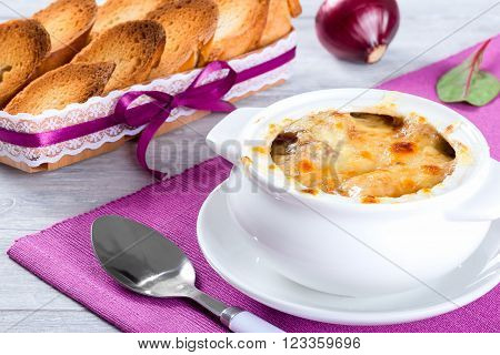 french onion gratin soup in a white pot close-up