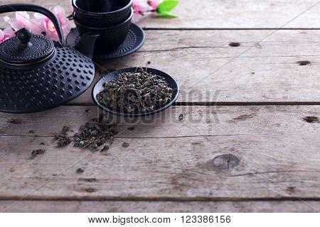 Green tea in bowl and traditional asian tea set on aged wooden background. Selective focus is on tea. Place for text.