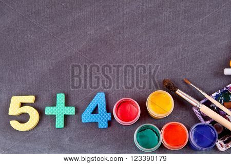 Plastic decorative bright colored figures and paints and brushes to paint on a black school board