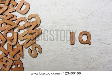 Word IQ (intelligence quotient) are made with wooden letters on an old white wooden background