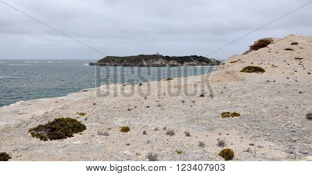 Indian Ocean seascape with a view of Hamelin Island from limestone cliffs at Hamelin Bay, under dark, stormy skies in Western Australia.