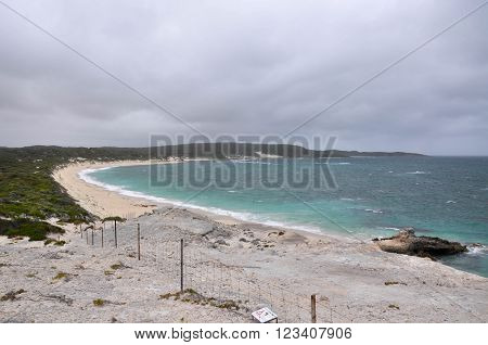 Elevated view of the secluded Foul Bay Beach from White Cliff Point with the turquoise Indian Ocean waters in Hamelin Bay under dark, stormy skies in Western Australia.