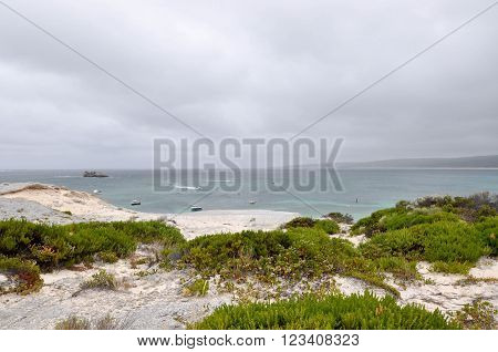Turquoise Indian Ocean seascape view from the limestone cliffs at Hamelin Bay beach under dark, stormy skies in Western Australia.