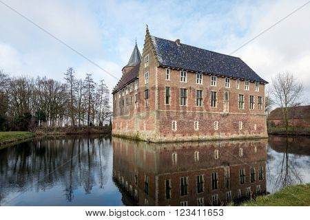 Dutch medieval castle built in 1474 reflected in the mirror smooth water surface of the moat on a beautiful day at the beginning of the spring season.