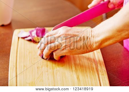 Woman cut red onion on cutting board