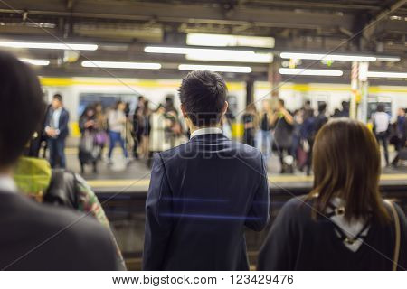 Passengers traveling by Tokyo metro. Business people commuting to work by public transport in rush hour. Shallow depth of field photo.