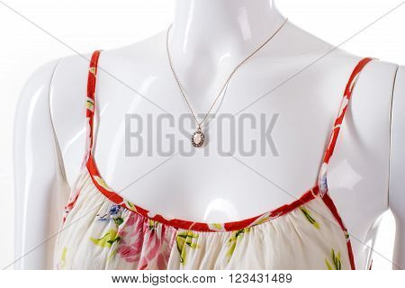 Chain with pendant on mannequin. Female mannequin wearing tiny pendant. Flax sarafan and precious pendant. Woman's fragile accessory with apparel.