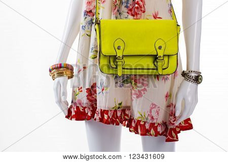 Purse and watch on mannequin. Female mannequin with lime handbag. Casual sarafan with bright bag. Lime purse and golden bracelets.