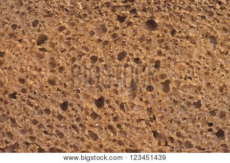 Brown bread, background texture, detailed look at the rye porous brown bread slice, macro view