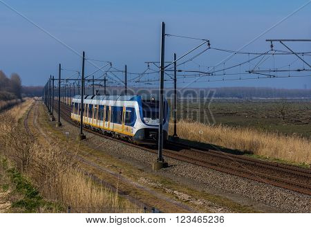 Flevoland the Netherlands - March 26 2016: Dutch snel train traveling through countryside.