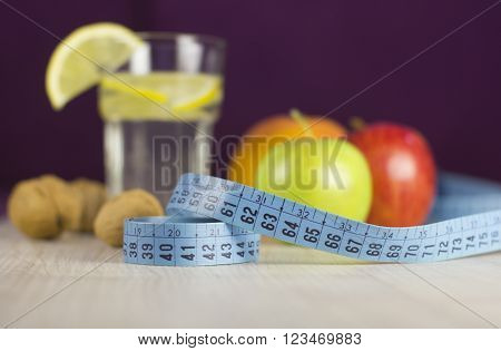 blue measure tape and fresh fruits with lemon drink for diet and healthy weight loss program