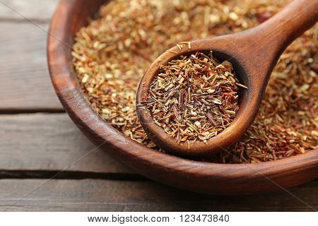 Rooibos tea in a round bowl on wooden table, close up