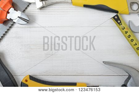 Top view of construction instruments and tools on wooden DIY workbench. Tape measure, wrench, hammer, pilers, screwdriver. Flat lay.