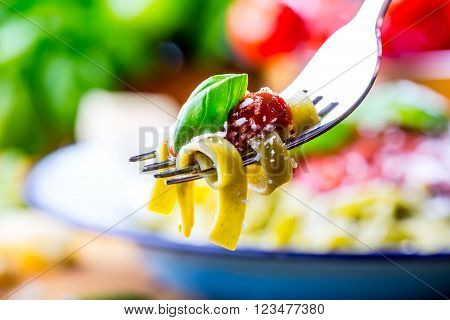 Pasta. Italian and Mediterranean cuisine. Pasta Fettuccine with tomato sauce basil leaves garlic and parmesan cheese. An old home kitchen with old kitchen utensils.