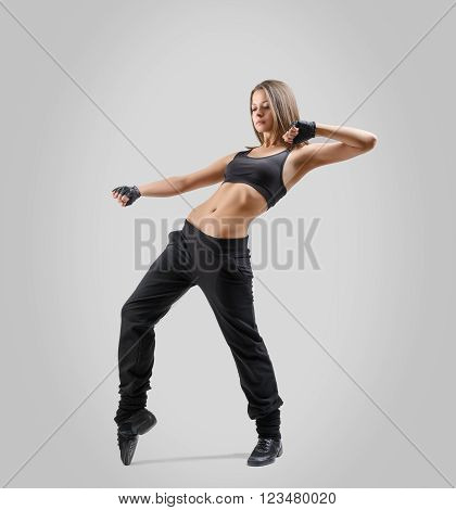 Girl dancer standing sideways and leaning back with lifted up left hand bent at the elbow. Right leg raised on tiptoes. Dance moves.