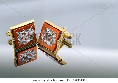gold cufflinks on a mirrored reflective background