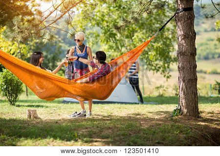 Couple in love toasting with beer in hammock with friend
