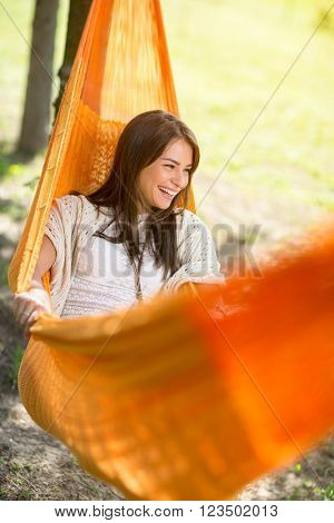 Likeable young woman  lying and enjoying in orange hammock outdoor