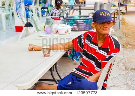 CHIANG RAI THAILAND - MARCH 20 : unidentified old asian leprosy man with cap drinking coffee in paper cup on March 20 2016 in Chiang rai Thailand.