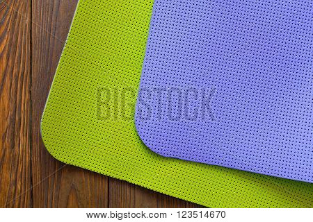 New yogamat green and purple on a wooden background. Facilities for training and yoga. Diagonal. The concept of love to a healthy lifestyle. Weight loss and fitness.
