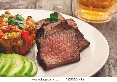 Roast beef on white plate with vegetable ragout. Delicious food