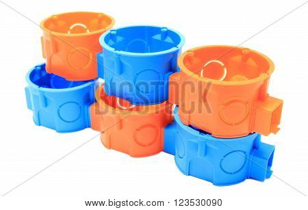 Stack of orange and blue plastic electrical boxes on white background, junction boxes, accessories for engineering jobs