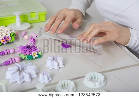 Artist makes jewelry from color Polymer Clay artist at work. Workshop. Hobby - Art Clay Modeling. Tools for Modeling. Handmade Production. Plasticine. Hands rolled plastic