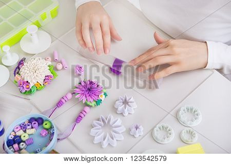 Artist makes jewelry from color Polymer Clay artist at work. Workshop. Hobby - Art Clay Modeling. Tools for Modeling. Handmade Production. Plasticine. Hands rolled plastic