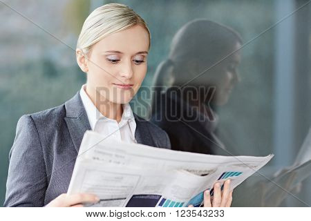 A young businesswoman reading the newpaper outside her office