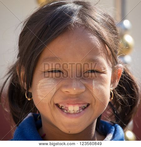INLE LAKE MYANMAR - JANUARY 12 2016: Unidentified young Myanmar girl with thanaka on her smile face is happiness. Thanaka is a yellowish-white cosmetic paste made from ground bark.