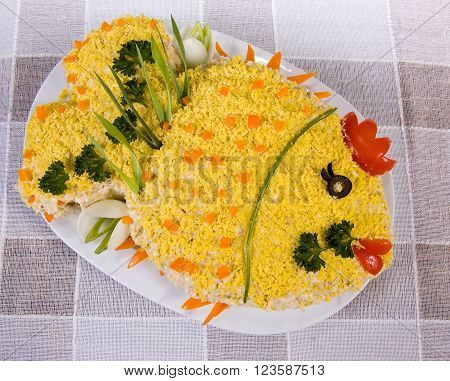 Fish salad in the shape of a fish, with boiled eggs and greenery on tablecloth
