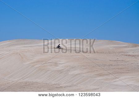 LANCELIN,WA,AUSTRALIA-SEPTEMBER 28,2015: Recreational motorbike rider on the white sand dunes under a blue sky in Lancelin, Western Australia.