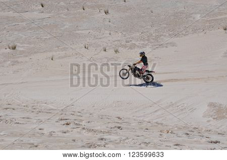 LANCELIN,WA,AUSTRALIA-SEPTEMBER 28,2015: Motorbike rider doing a wheelie on the white sand dunes in Lancelin, Western Australia.