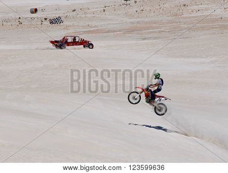 LANCELIN,WA,AUSTRALIA-SEPTEMBER 28,2015: Dune buggy and jumping motorbike rider at the white sand dunes recreational attraction in Lancelin, Western Australia.