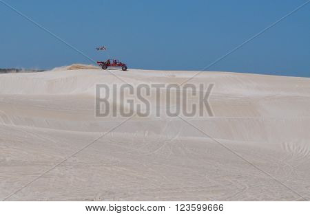 LANCELIN,WA,AUSTRALIA-SEPTEMBER 28,2015: Red dune buggy with checkered flag and driver racing across the pristine white sand dune landscape in Lancelin, Western Australia.