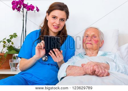 Caring doctor helping a senior patient to use a digital tablet.